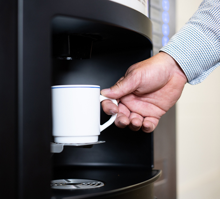 Kaffeetasse wird unter Standautomat gehalten